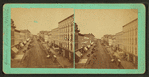 Street scene with buildings, trolley tracks, store fronts, and carriages.