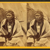 Portrait of native American man in front of teepee.