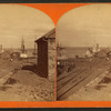 Railroad tracks and steamboats moored at piers along the lake.