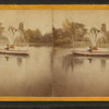 Man in boat on lake, next to fountain.