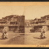 View of two Zuni individuals in front of Pueblo.