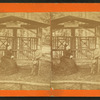 View of a woman and a boy, sitting on covered bench called 'Flora's Bower.'