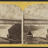 Suspension bridge, river and falls in the distance.