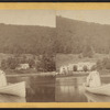 View on lake of rowboat in foreground, buildings in the shore beyond.