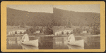 View on lake of rowboat in foreground, buildings in the shore beyond.