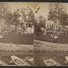 Women and children sitting on lawn of a large building, probably a hotel.