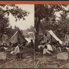 Group of people, including children, with two tents and a woven basket.