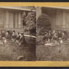 Group portrait of women sitting on the grass in front of a house.