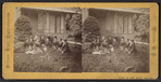 Group portrait of women sitting on the grass in front of a house.