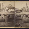 View of a building surrounded by oil derricks and barrels.