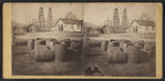 View of a building surrounded by oil derricks and barrels.