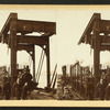 Bridge under construction with train on tracks.