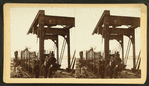 Bridge under construction with train on tracks.