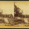 Group of men and women posed on rocky outcrop.