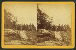Group of men and women posed on rocky outcrop.