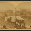 A view taken from the rear of the P. R. R. depot. In the middle ground are seen the stores and offices of the Cambria Iron Co., and in the foreground are coffins and bodies just arrived from the morgues and ready for shipment.