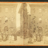 Women and children in front of narrow three story building.