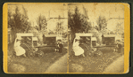 A boy and girl sitting outside and playing with dollhouses, baby carriage and doll.