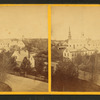 View of town, with houses and church spires, from above.