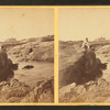 View of some beach goers sitting on the rocks.