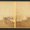 Group of people sitting on rocks, in front of a tent and a tipi.
