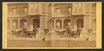 People in coach with African American coachmen, in front of house.