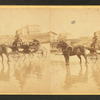 Coach on beach, and houses in the distance.