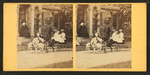 Children in a goat cart in front of house.