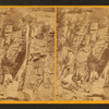 Three men resting on the rocks near a waterfall.