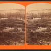 View of men standing among foundations of buildings (destroyed by fire?)