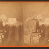 A cat wearing a mask, and sitting up at a table with a book on it.