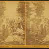 Group around a campfire, woman pouring from a coffee pot.