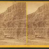 Cañon wall, boats on bank of river.
