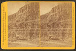 Cañon wall, boats on bank of river.