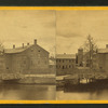 View of unidentified industrial buildings on a river.