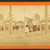 Group lined up in front of a row of shacks.