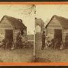 Uncle Abe's schoolhouse and scholars. [Man in a top hat in front of a shack with several boys with books.]