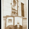 Dailey Paskman outside unidentified theatre with promotional window and lobby cards for Dailey Paskman's Radio Minstrels, including a poster for Primrose Semon ["The Titian Clown"] and Nate Busby