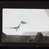 Harry Houdini suspended upside down from a building, holding out a straightjacket