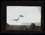 Harry Houdini suspended upside down from a building, holding out a straightjacket