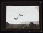 Harry Houdini suspended upside down from a building, holding out a straightjacket
