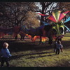 Two children approaching a large dragon puppet designed by Ronnie Aswell and operated by seven people