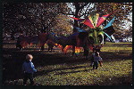 Two children approaching a large dragon puppet designed by Ronnie Aswell and operated by seven people