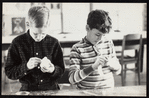 Two children sculpting hand puppet heads from styrofoam