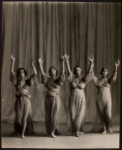Four dancers with arms raised in gesture of praise.