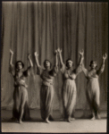 Four dancers with arms raised in gesture of praise