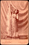 Studio photo of Loie Fuller in a costume with flower garlands.