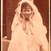 Loie Fuller in veil, sitting on a pillar