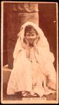 Loie Fuller in veil, sitting on a pillar