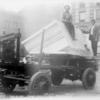 Two men with a block of marble on a cart